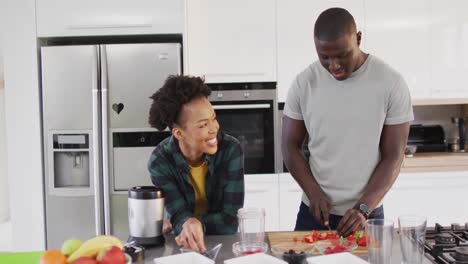Video-of-happy-african-american-couple-preparing-meal-together-in-kitchen