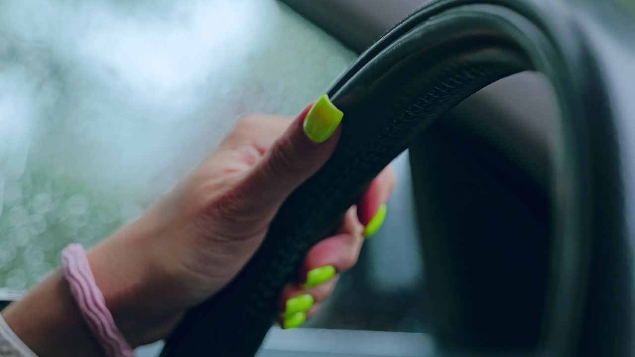 Cinematic slow motion, female hand with nails gripping car steering wheel