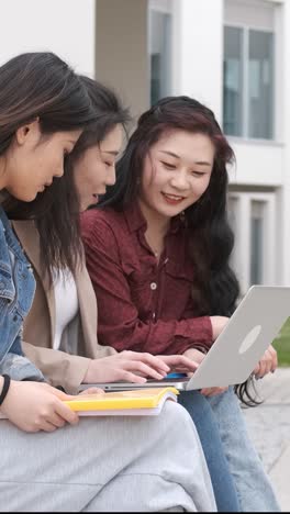 three asian girl students using the laptop at break time sitting on campus