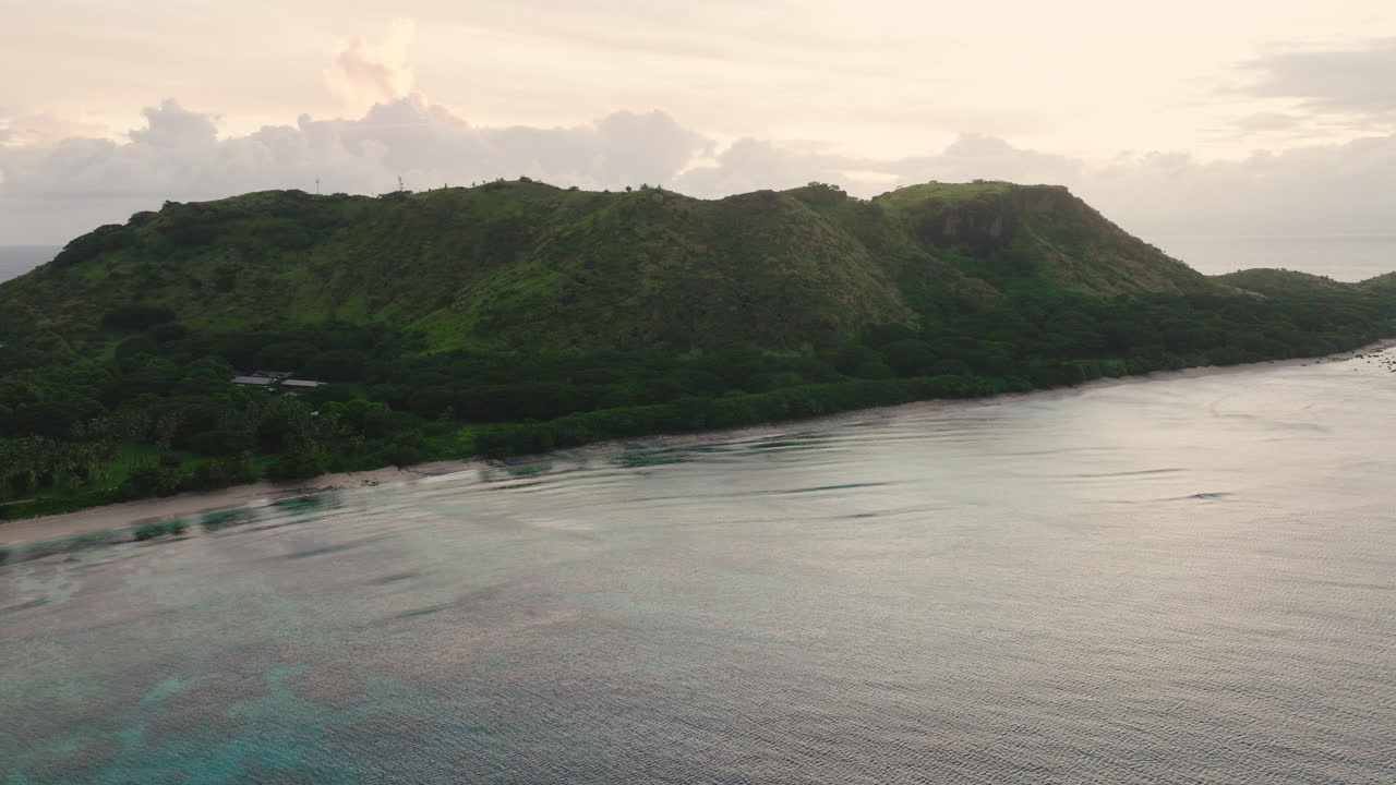 Tropical shoreline with boats and misty hill backdrop in calm morning light