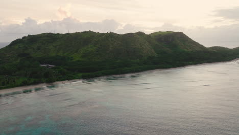 tropical shoreline with boats and misty hill backdrop in calm morning light