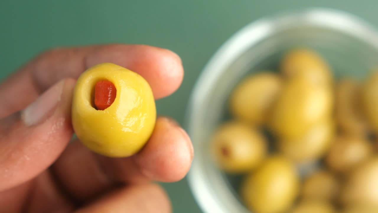 Hand holding a stuffed green olive