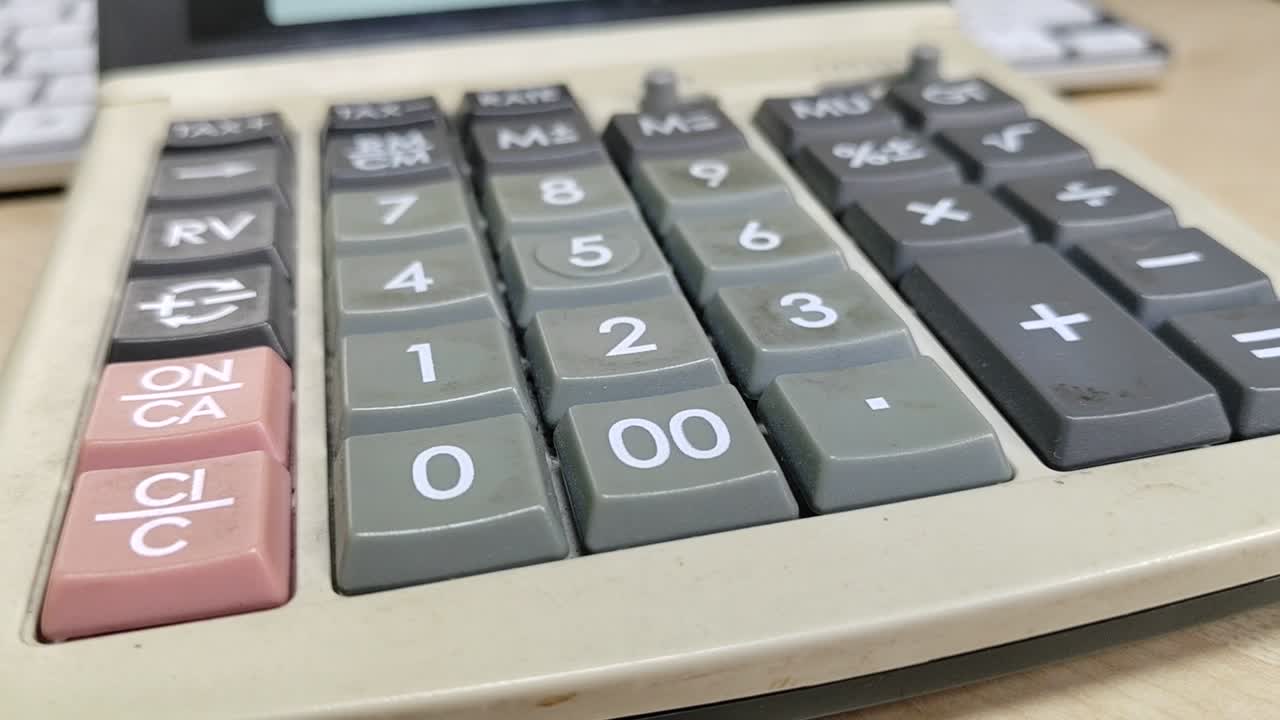 A well-worn, large calculator sits close-up on a desk. Its faded appearance shows frequent use, a testament to countless computations.