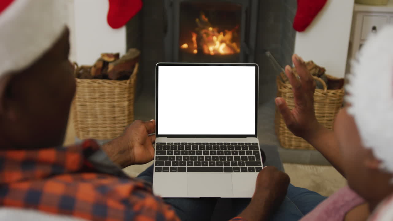pareja afroamericana en sombreros de santa haciendo llamada de video de navidad portátil, con espacio de copia en la pantalla