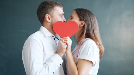 couple kissing through a red heart