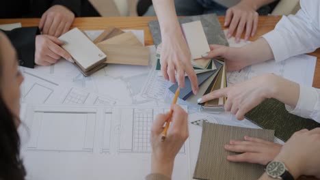 a team of interior designers collaborates over a table, examining architectural plans, fabric swatches, and color palettes, planning a design project