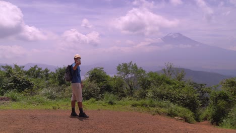 male solo hiker taking selfies on top of mountain looking out towards mount fuji