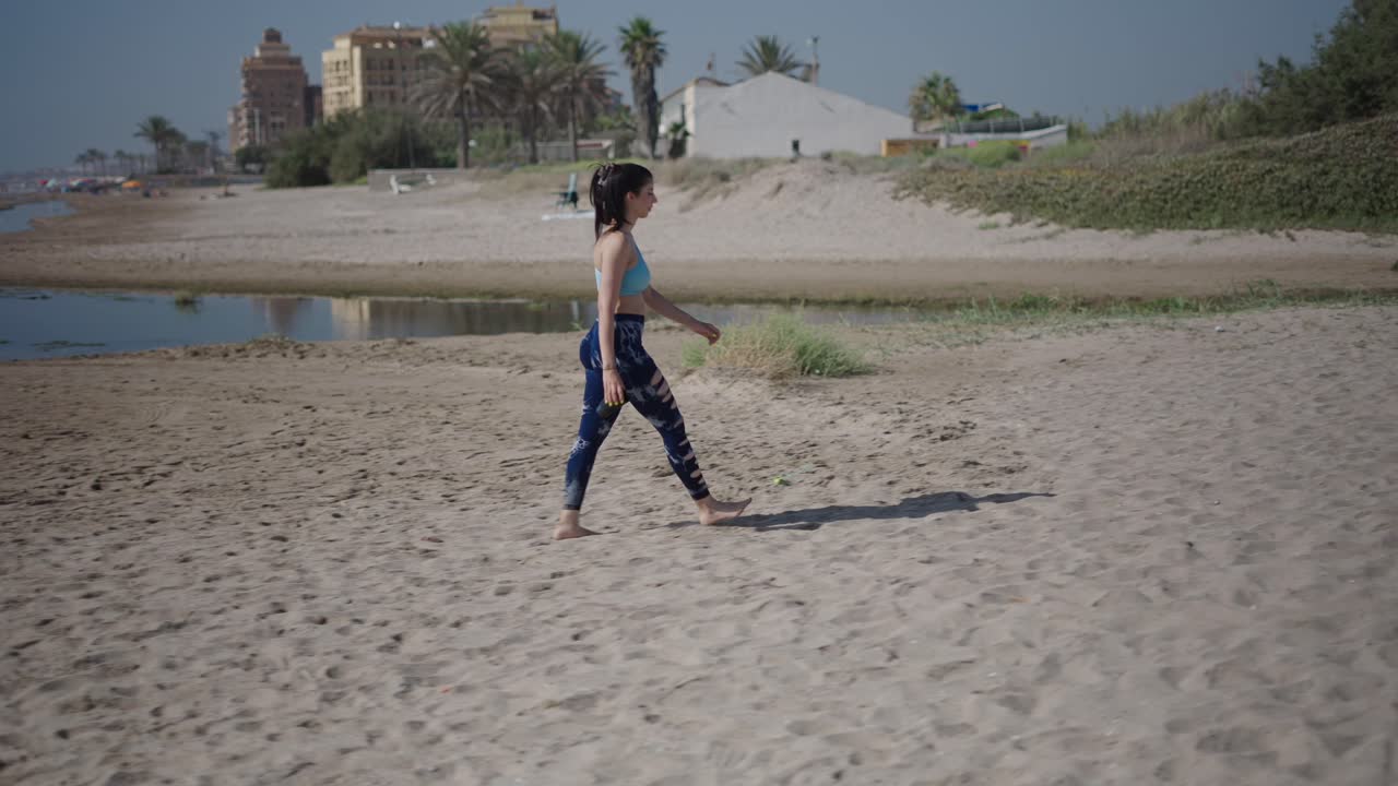 Woman Walking on the Beach and Drinking