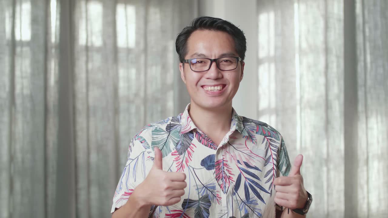 카드보드 상자를 가진 아시아 남자의 근접 사진 웃음과 엄지손가락을 보여주는 새로운 집에서 카메라에 대한 제스처