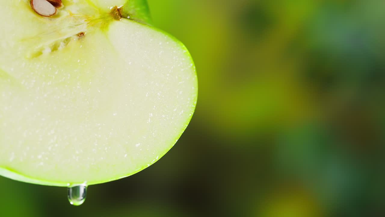 Goccia d'acqua che cola da mezza mela verde fresca