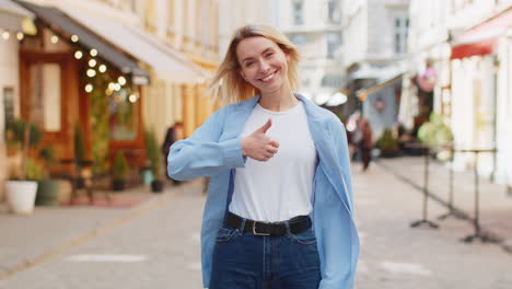 Una-Turista-Feliz-Mostrando-Sus-Pulgares-Hacia-Arriba-Como-Algo-Positivo,-Una-Buena-Retroalimentación-Positiva-En-Las-Calles-De-La-Ciudad