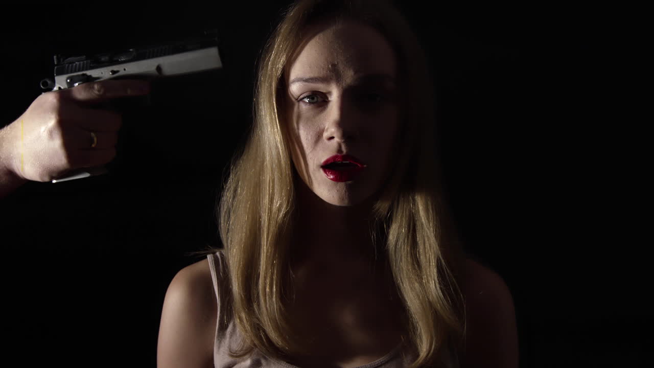 무서워하는 여자 머리에 총을 가하는 남자