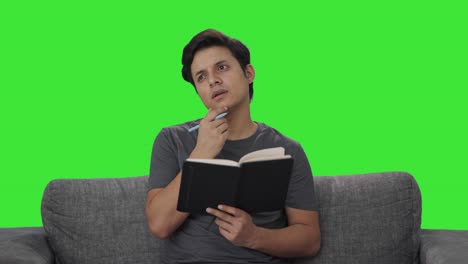 thoughtful indian man writing in diary green screen