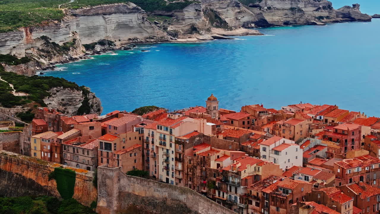 Aerial drone shot over the historic coastal town of Bonifacio in Corsica, France. High view of the rocky steep cliff and the turquoise sea. Ancient Citadel overlooking the rugged coastline