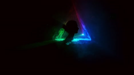 imagen de una niña en un fondo claro de diferentes colores moviéndose en la oscuridad. el humo llena el triángulo con la cabeza de la niña. proyector.
