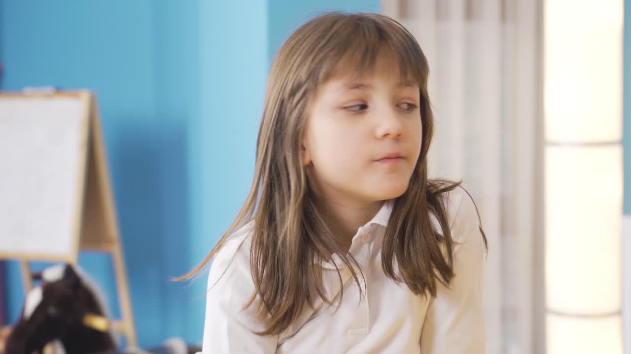 una niña solitaria mirando pensativa por su habitación.