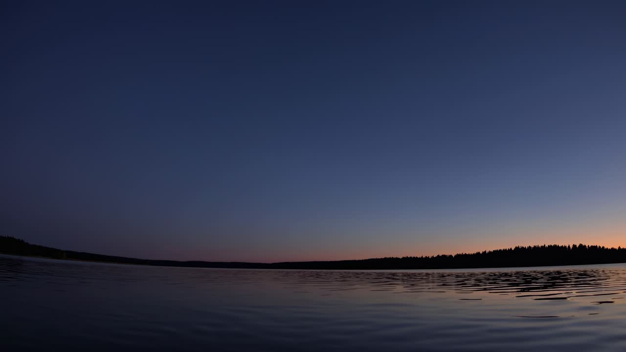 Serene sunset over a calm lake, captured in a wide-angle video