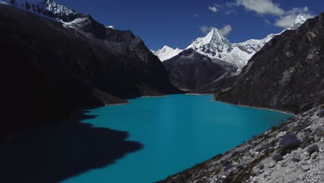 aerial shot ascending the valley slope at laguna parón with the snow-capped paramount pictures mountain