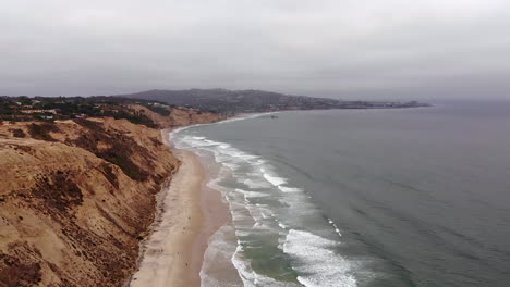 Waves-crash-near-expansive-cliffside-at-Torrey-Pines-on-cloudy-day