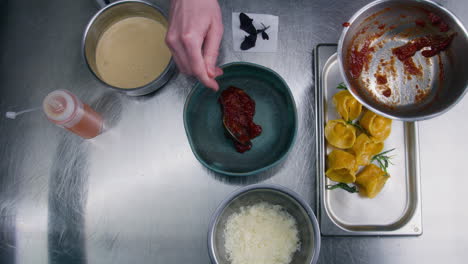 cook pours sauce on plate and lays out ravioli