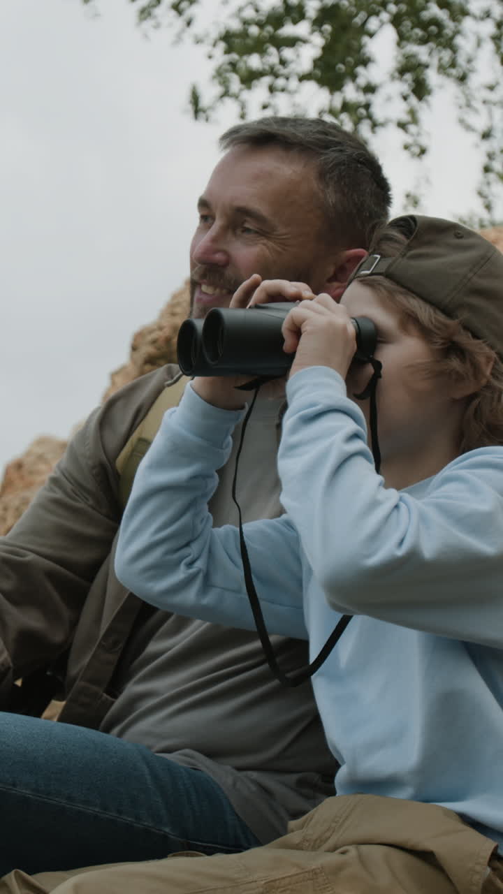 Padre e figlio che osservano la natura con il binocolo