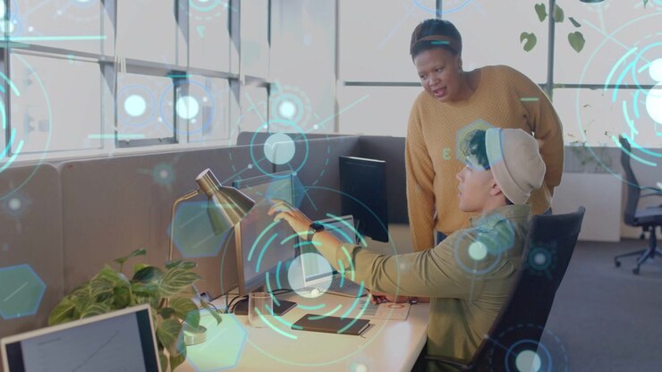 Mand rækker ud mod skærmen, kvindelig leder læner sig frem og rådgiver, mens et hologram UI animerer til en teknisk gennemgang.