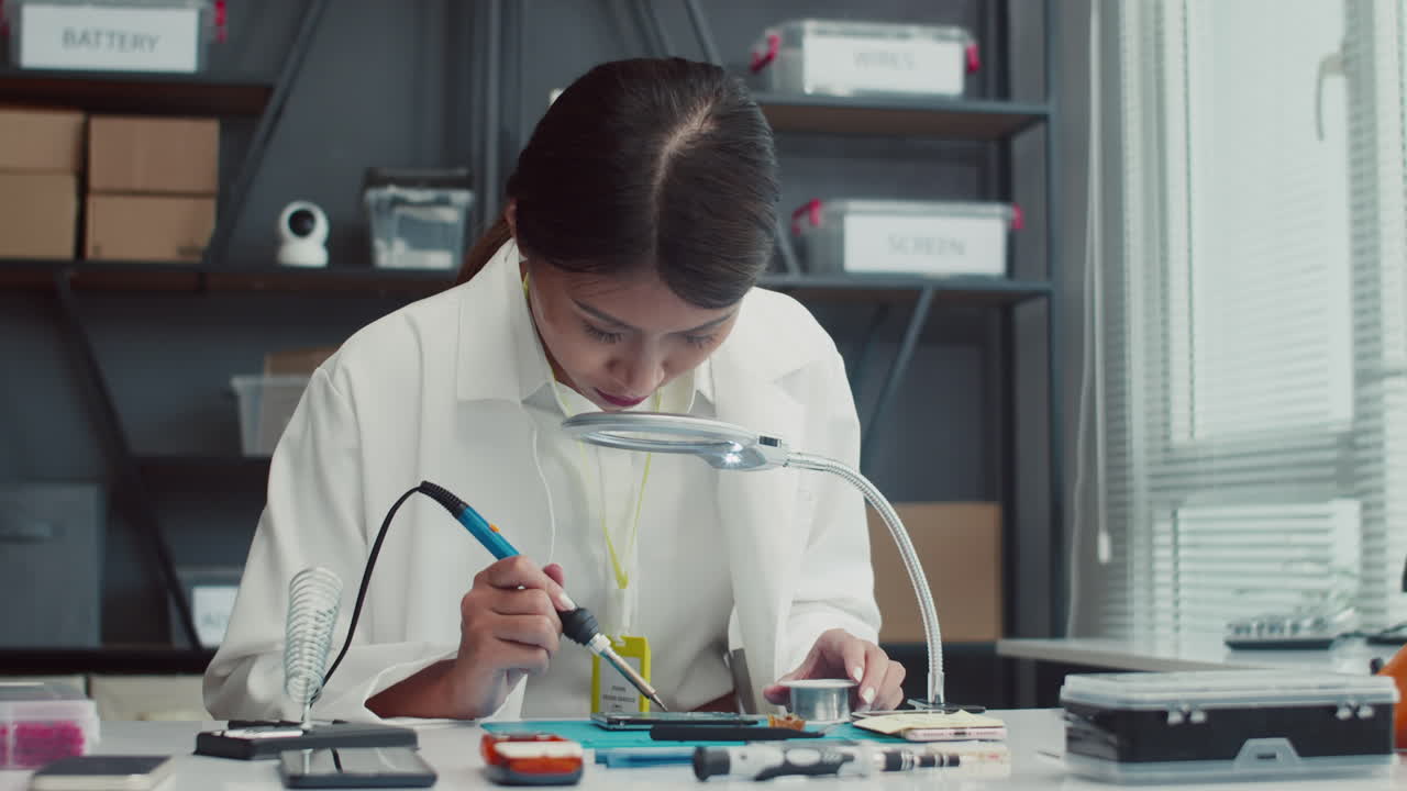 Woman Working with Soldering Iron when Repairing Smartphone