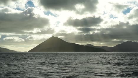 cámara lenta: vista matutina del sol, el cielo, las nubes, las colinas y el océano desde un barco en los sonidos de marlborough, nueva zelanda