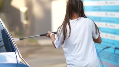 mujer lavando un coche en un lavado de coches de autoservicio