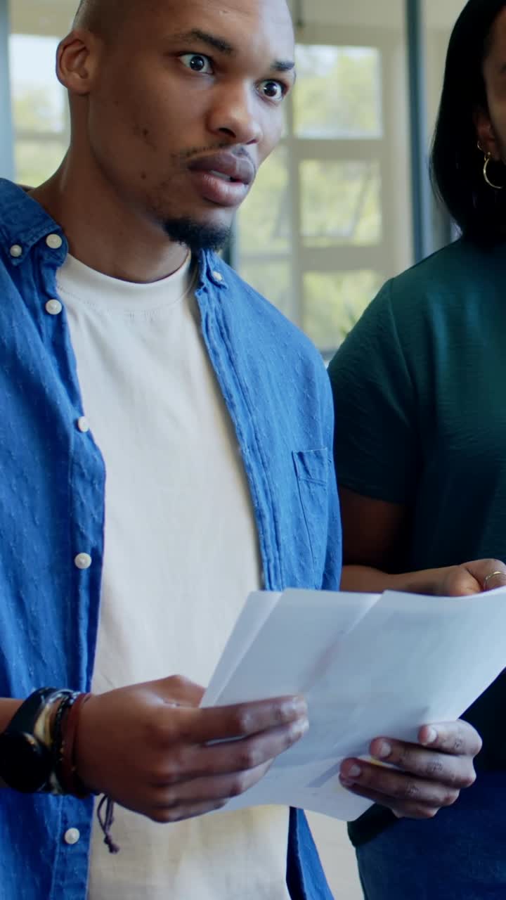 Vertical video: Reading man and woman watching host pointing at laptop chart in meeting for review