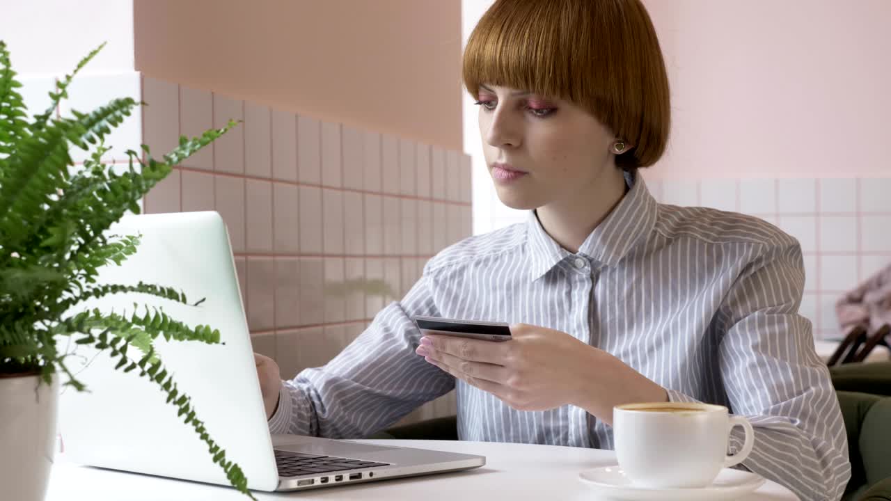 молодая красивая рыжеволосая девушка делает онлайн-покупки в интернете, ноутбук, кредитная карта, банковское дело, приложение. 60 кадров в секунду