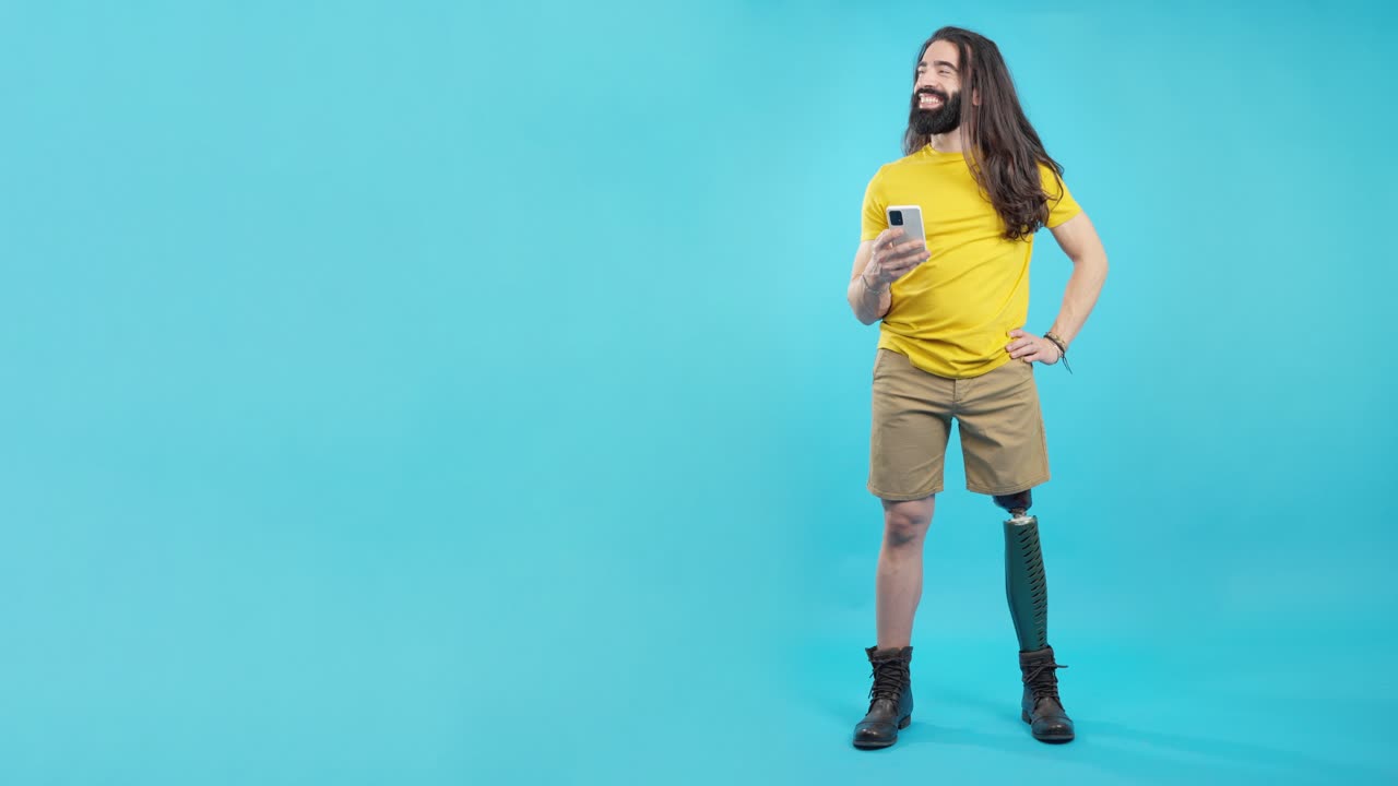 Confident Man with Prosthetic Leg Using Smartphone on Blue Background