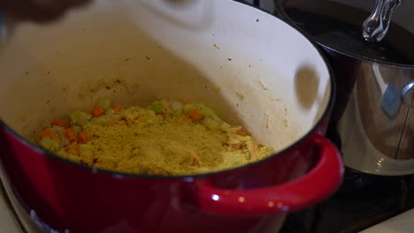 adding measuring spoon of cumin seasoning to vegetables in pot, closeup