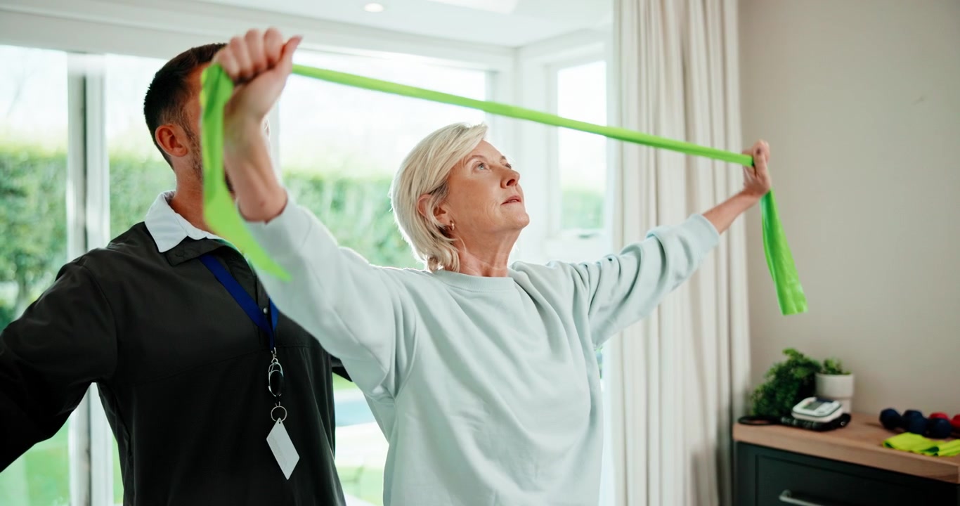 Physical Therapist Assisting Senior Woman with Resistance Band Exercise