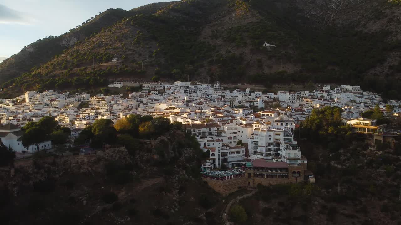 Mijas'ın beyaz kasabası üzerinde parlayan gün batımı güneşi, havadan görünüm.