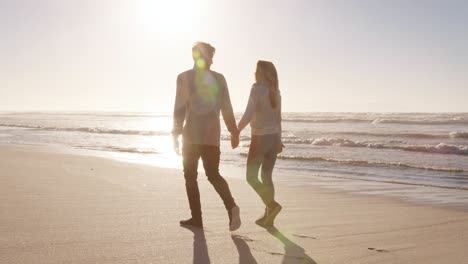 rear view of loving couple walking along winter beach together