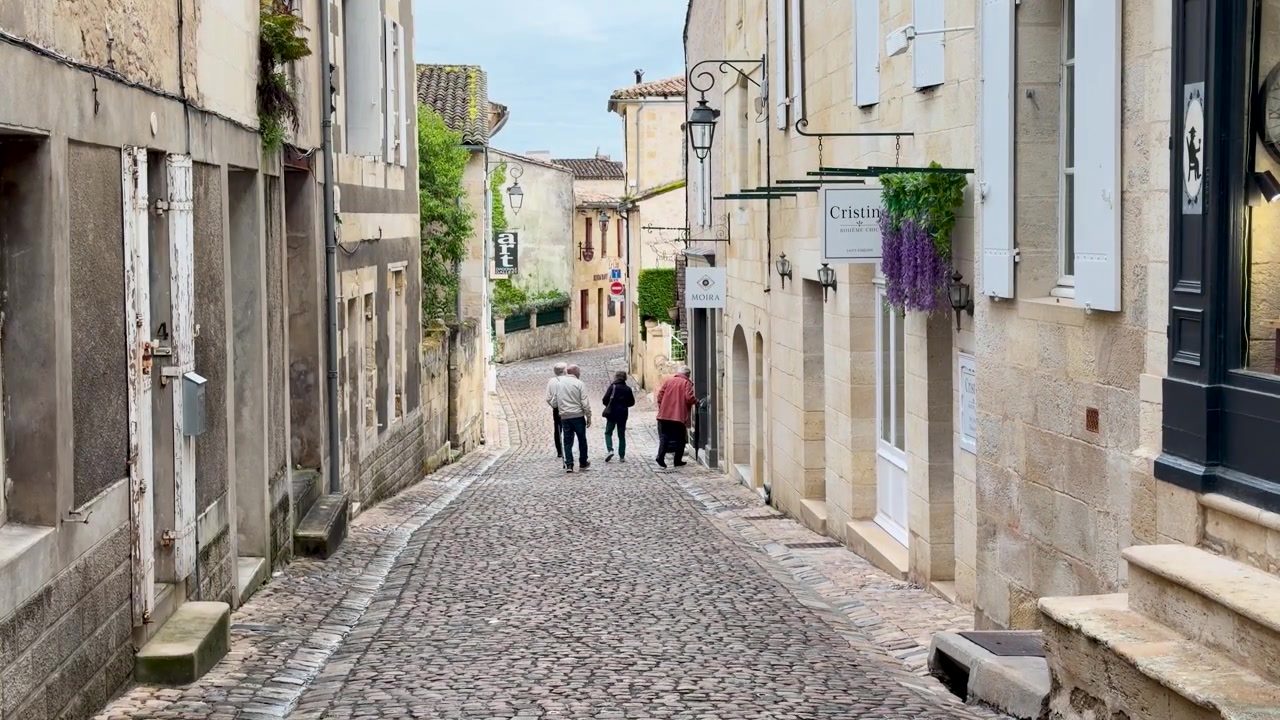 Turisti anziani caucasici camminano attraverso uno stretto vicolo medievale con edifici storici in pietra calcarea.