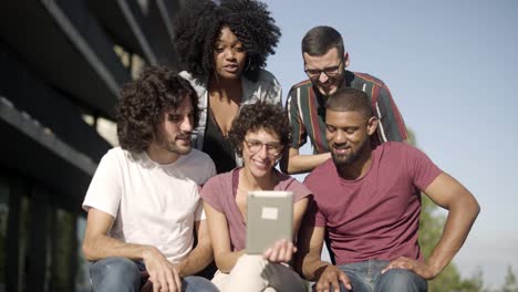 smiling friends having video call through tablet