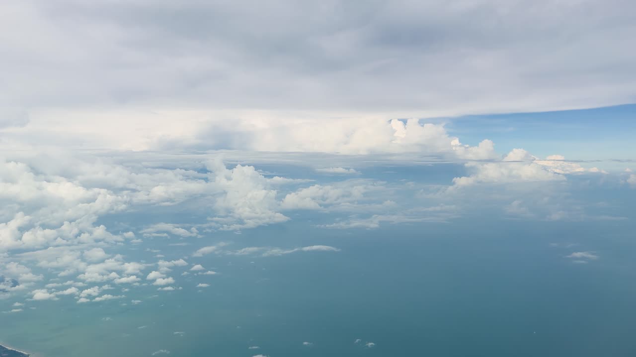 穏やかな海に広がる柔らかな雲と、曇り空を飛行機から捉えた安定感のある眺め。
