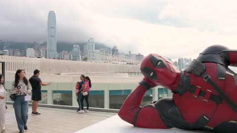 in front of hong kong's skyline, locals and tourists gather to see the 8-meter deadpool figure, part of disney's promotion for the "deadpool and wolverine" film.