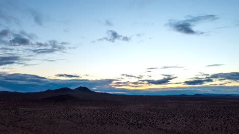 pull back aerial hyper lapse in the mojave desert with mountains in the otherwise empty, barren landscape at sunset