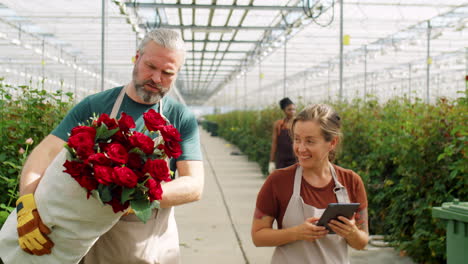 Kollegen-Sprechen-Und-Gehen-Mit-Rosen-Und-Tablet-Im-Blumengewächshaus