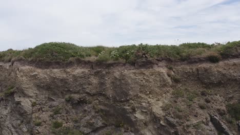 packed sedimentary conglomerate caps rocky cliffs, green grass on top