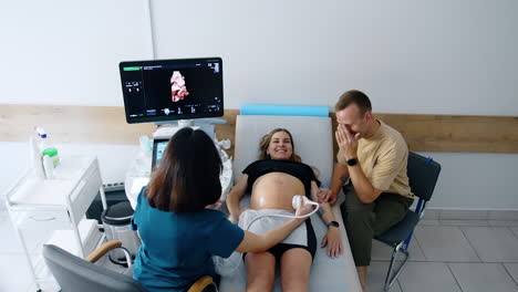 examining the pregnancy in the hospital. caucasian couple is having ultrasound check up on the last stages of expecting. top view.