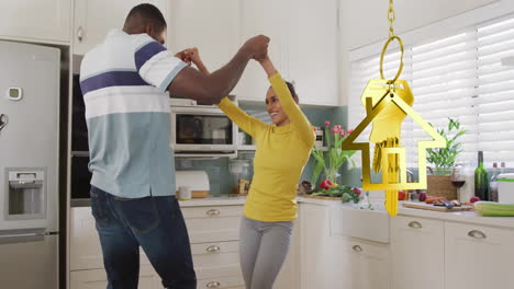 animation of gold house key over diverse couple dancing in kitchen