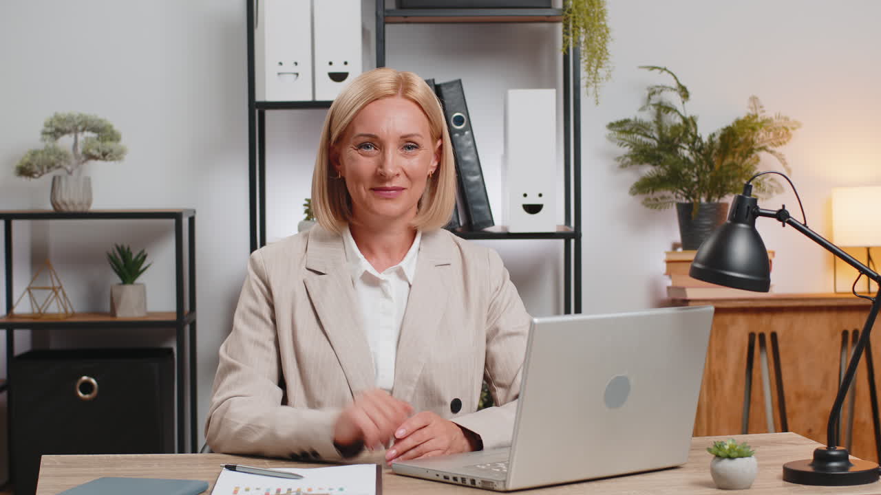 Portrait of mature businesswoman in suit looking at camera after using laptop at home office desk