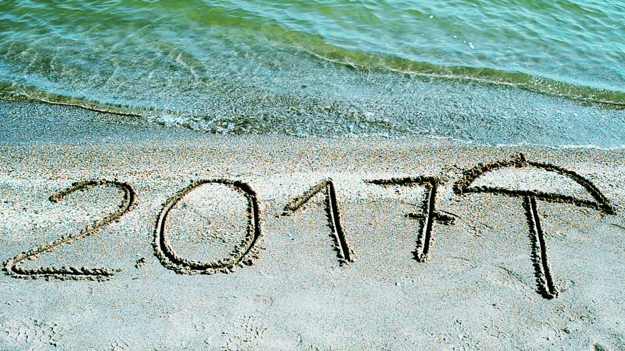 2017 som en inskription i sandet, på stranden. Optagelse på stranden.