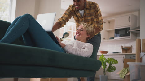 couple unpacking boxes after moving into new home together making video call on  laptop