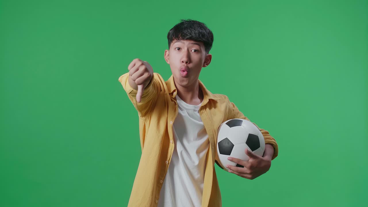 공을 들고 있는 아시아 소년 은 녹색 스크린 배경 에서 축구 를 응원 하는 동안 패자 들 을 조롱 하는 몸짓 을 하고 있다