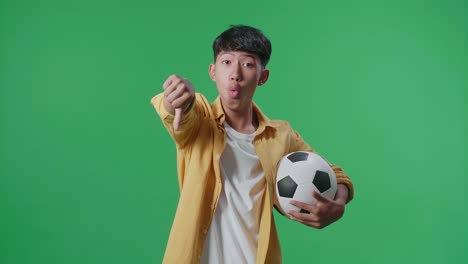 공을 들고 있는 아시아 소년 은 녹색 스크린 배경 에서 축구 를 응원 하는 동안 패자 들 을 조롱 하는 몸짓 을 하고 있다
